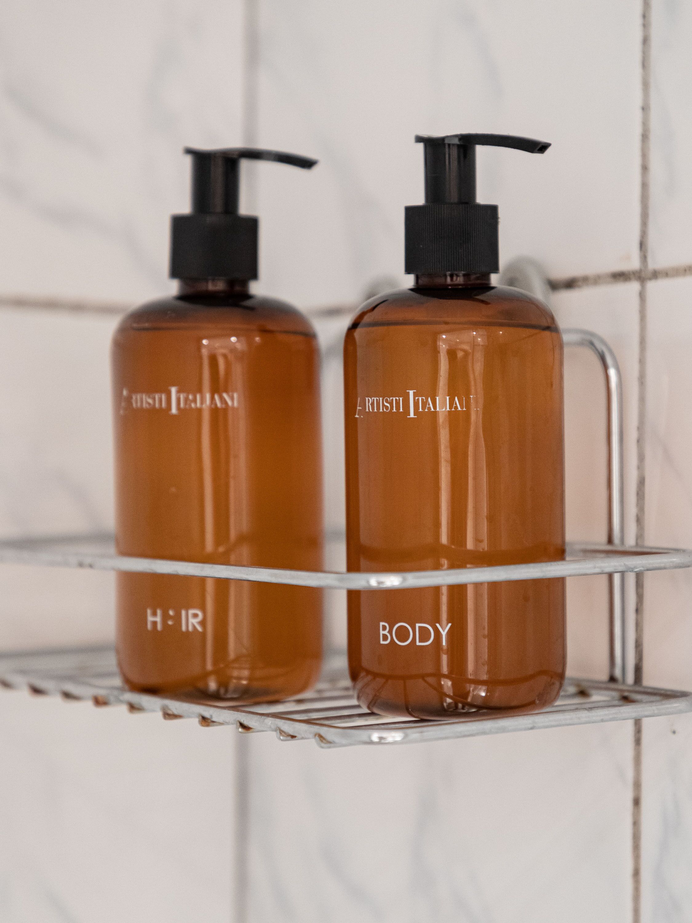 Two bottles of hair and body care products on a metal shelf.