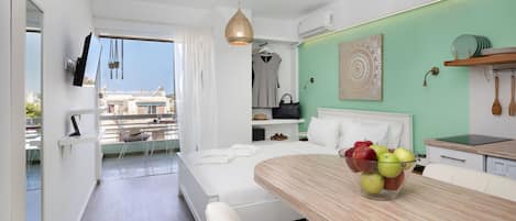 Ett modernt hotellrum med en balkong, en matplats med en fruktskål och en vägg som har en accentfärg i grönt.