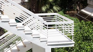 A white outdoor staircase with multiple levels, surrounded by lush green foliage. - Seaside Secret by BluPine (Vari-Voula-Vouliagmeni)