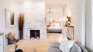 A modern living room with a fireplace, a sofa, and a bed in the background. - Voted best bridal /wedding family stay in the city! Come experience the memories (Cincinnati)