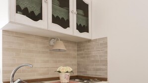A kitchen with white cabinetry, a sink, and a stove. - La Maison Romantique (Naples)