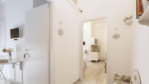 A modern, well-lit hallway with a dining area on the left, a sofa on the right, and a kitchen in the background. - La Maison Romantique (Naples)