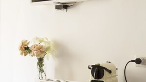 A white desk with a coffee maker, a cup, and a vase with flowers. - La Maison Romantique (Naples)