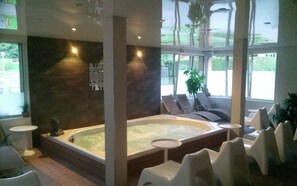 A spa area with a hot tub, lounge chairs, and a view of the outdoors. - Camping Bois de Gravière (Besse-et-Saint-Anastaise)