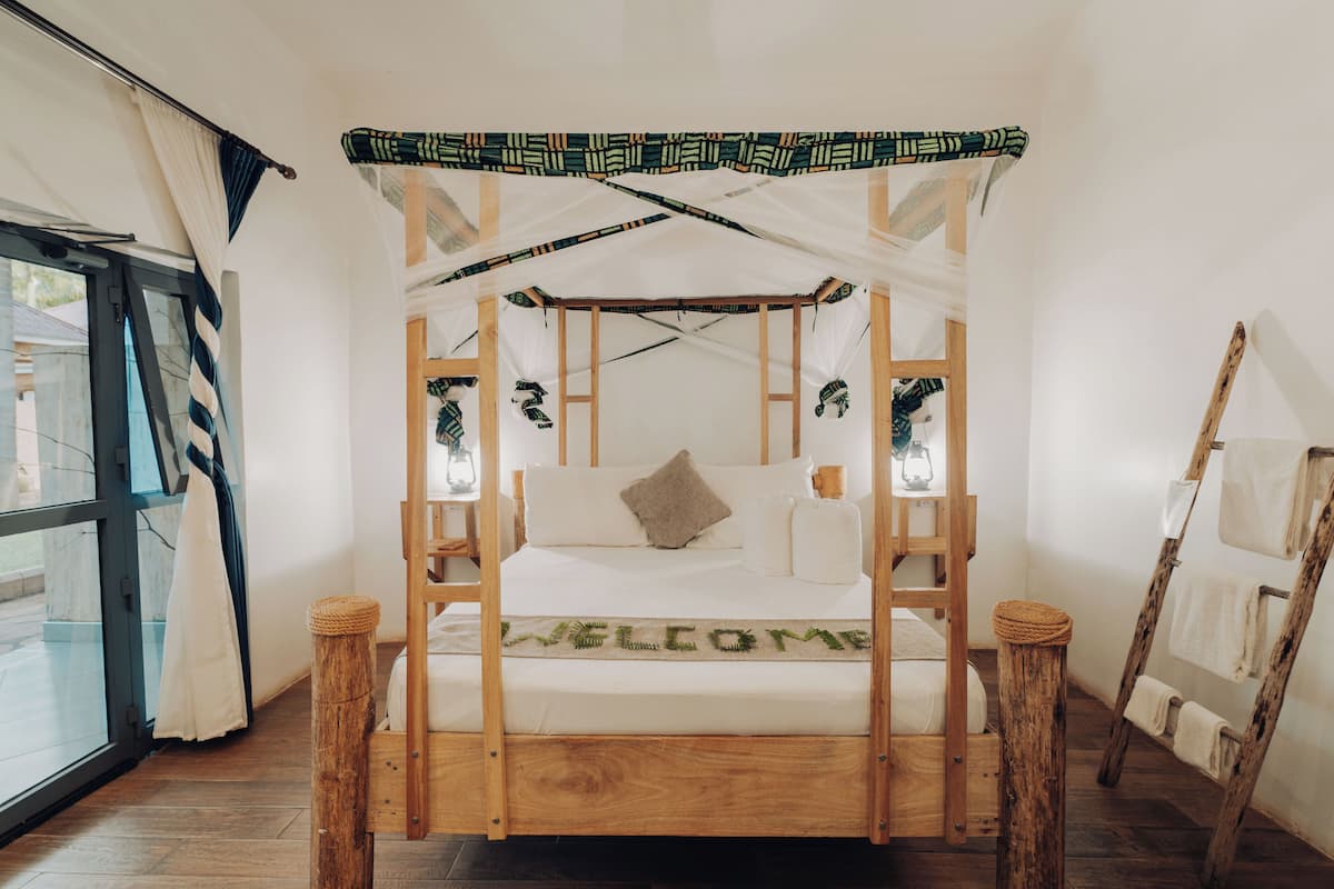 A bed with a canopy, a ladder, and a welcome mat.