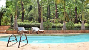A pool area with two lounge chairs and a pool. - Chanya Lodge (Moshi)