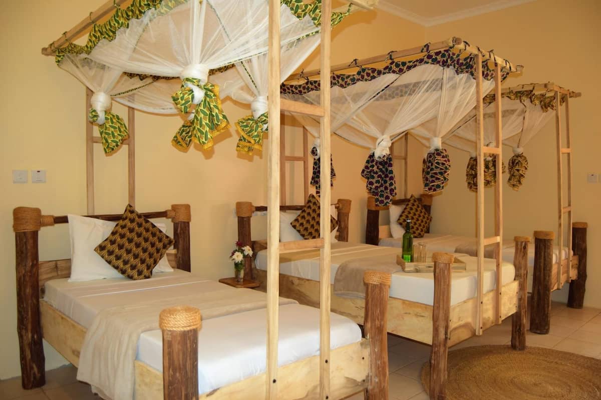 A room with four wooden beds, each with a canopy bedspread and a woven headboard.