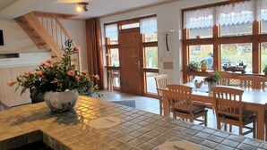 A kitchen with a tiled backsplash, wooden chairs, a dining table, and a staircase. - Ferienhof Cohrs - Ferienhäuser (Bispingen)