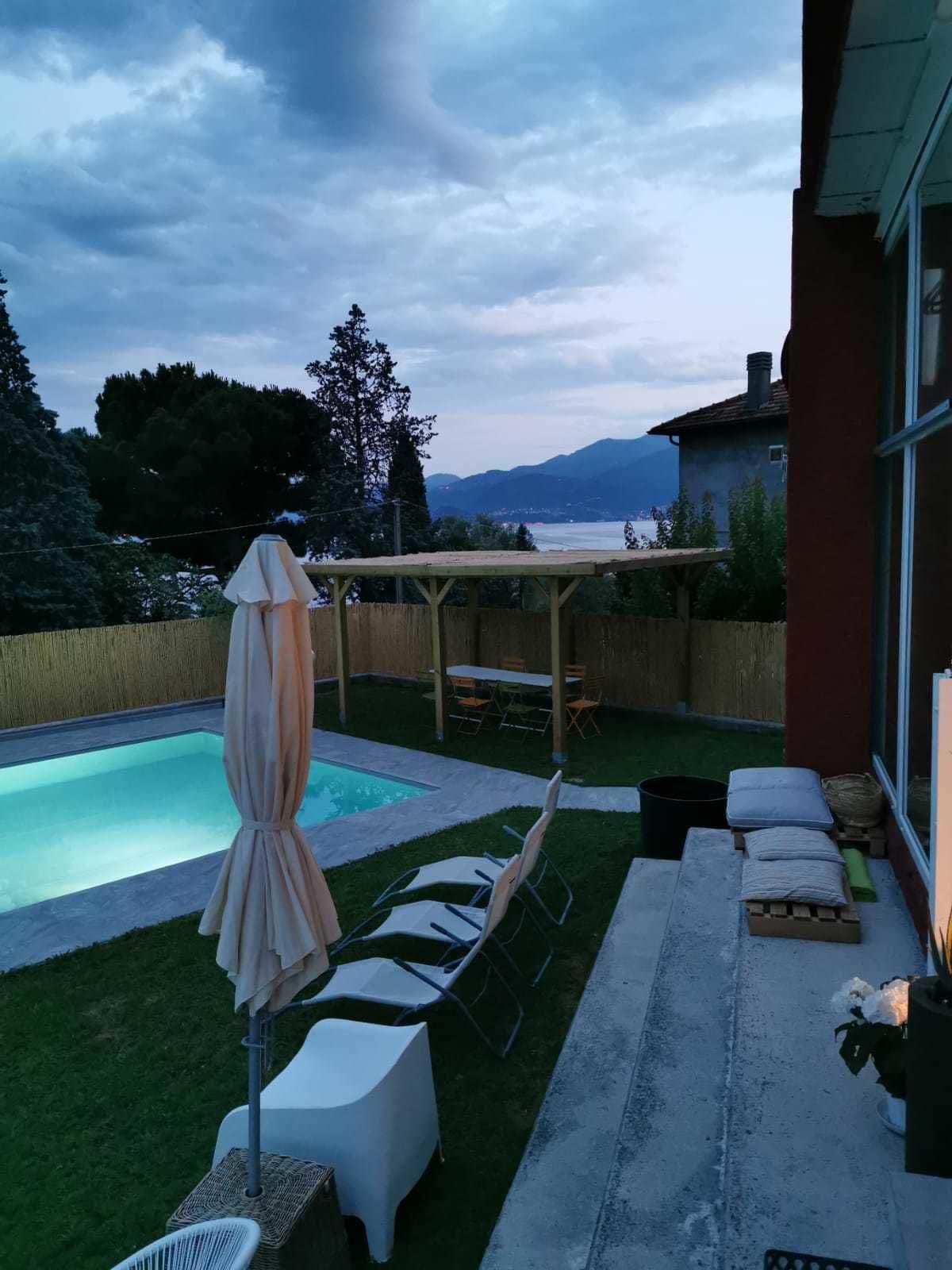 Un patio trasero con piscina, sillas de descanso y un pérgola.