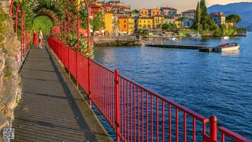 Eine rote Fußgängerbrücke über einem Gewässer, im Hintergrund bunte Gebäude.