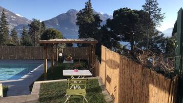 Un jardin avec une piscine, une pergola en bois et une table entourée de chaises.