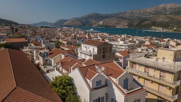 A coastal town with terracotta-tiled buildings, a marina, and hills in the background.