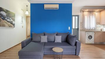 A modern living room with a sectional sofa, a round coffee table, and a washing machine in the background.