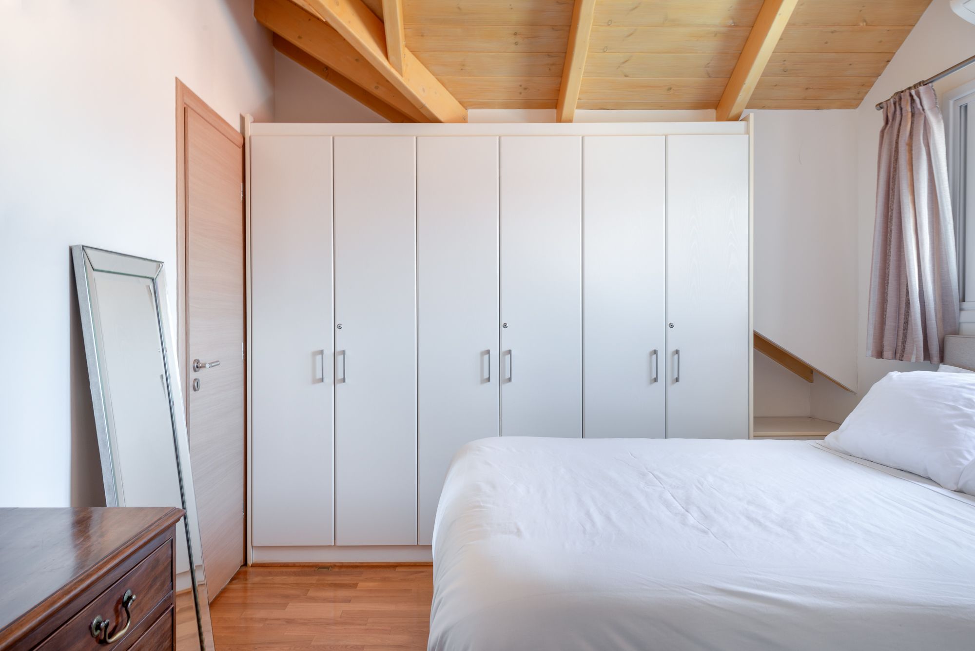 Una camera da letto con un letto grande, un armadio e un soffitto in legno.