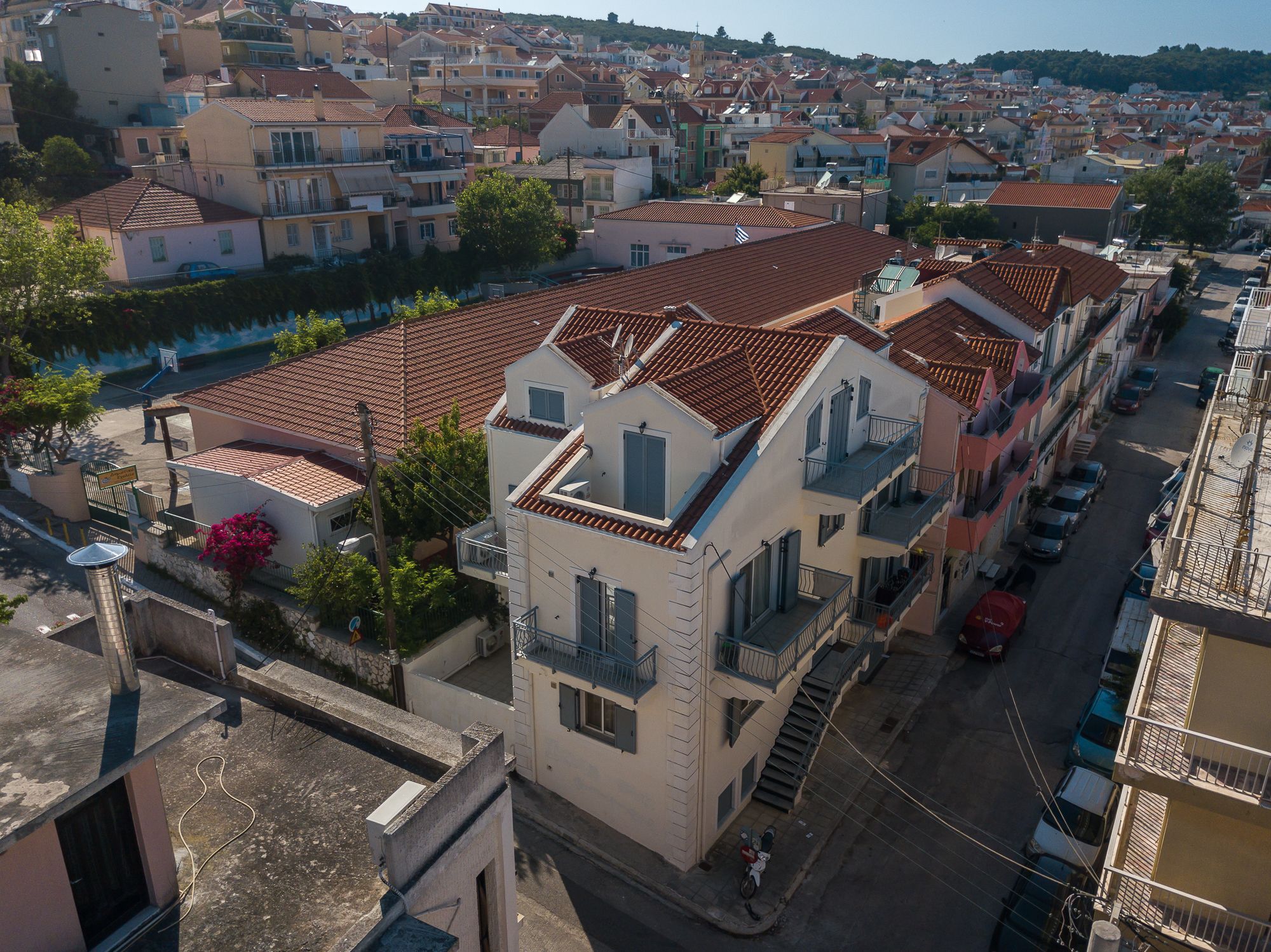 A residential area with terracotta-tiled roofs, balconies, and a narrow street.