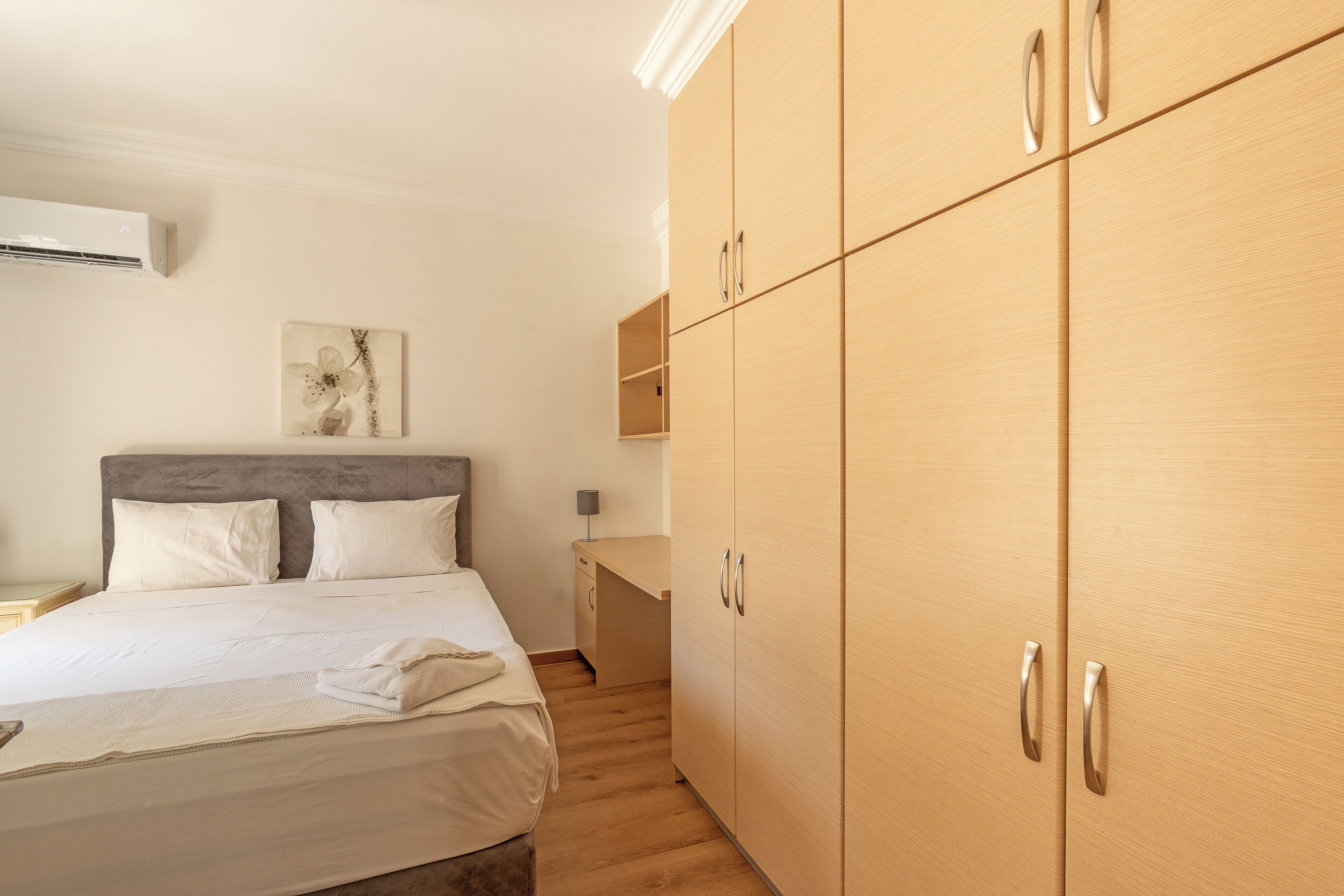 A hotel room with a bed, a desk, and a wardrobe.