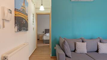 Habitación de hotel con pared de acento color turquesa, sofá gris, radiador blanco y un cuadro de la Torre Eiffel.