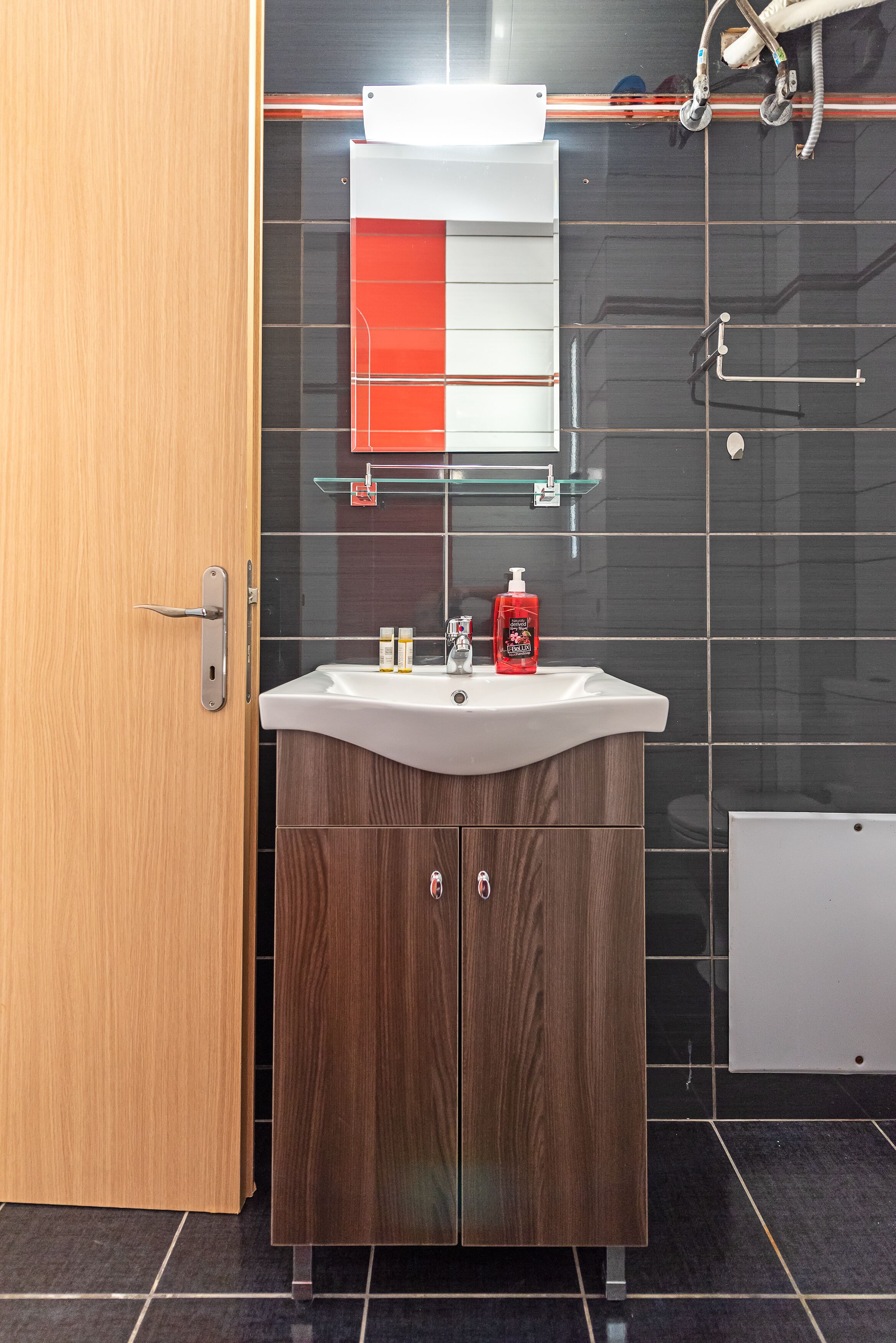 A modern bathroom with a wooden vanity, a white sink, and a glass shower enclosure.