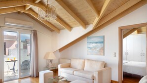 A spacious living area with a high ceiling, a glass coffee table, a sofa, and a painting of a beach scene.