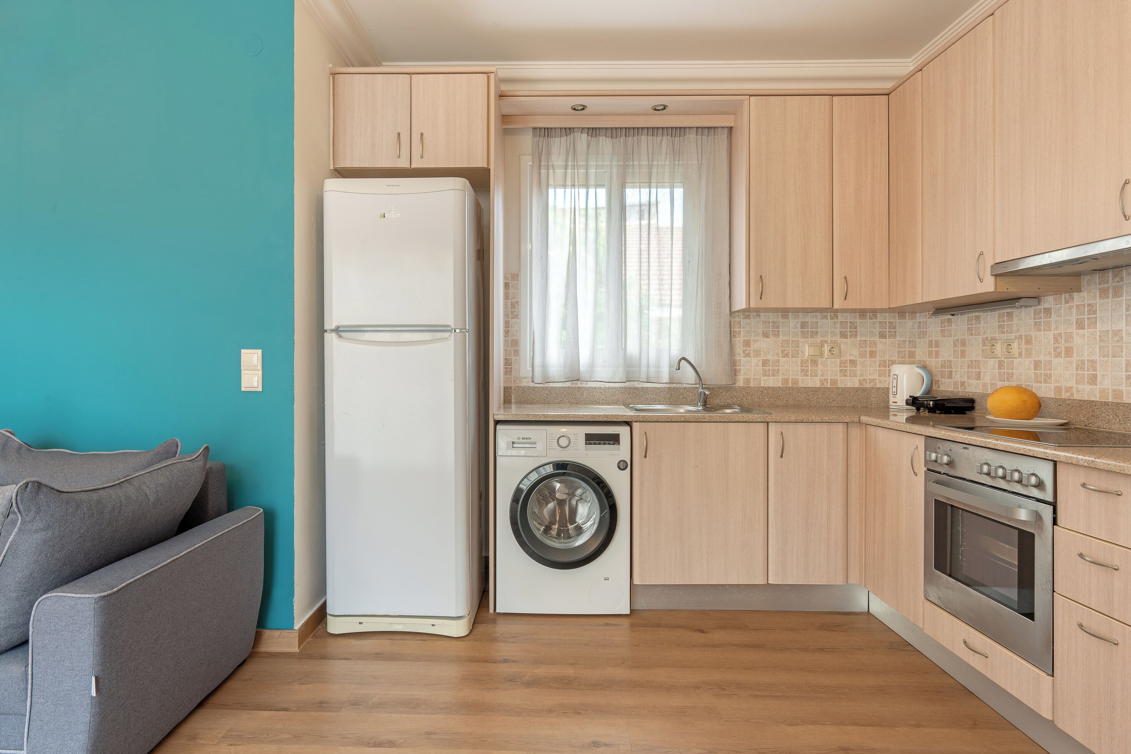 A compact kitchen with a washing machine, oven, and a refrigerator.