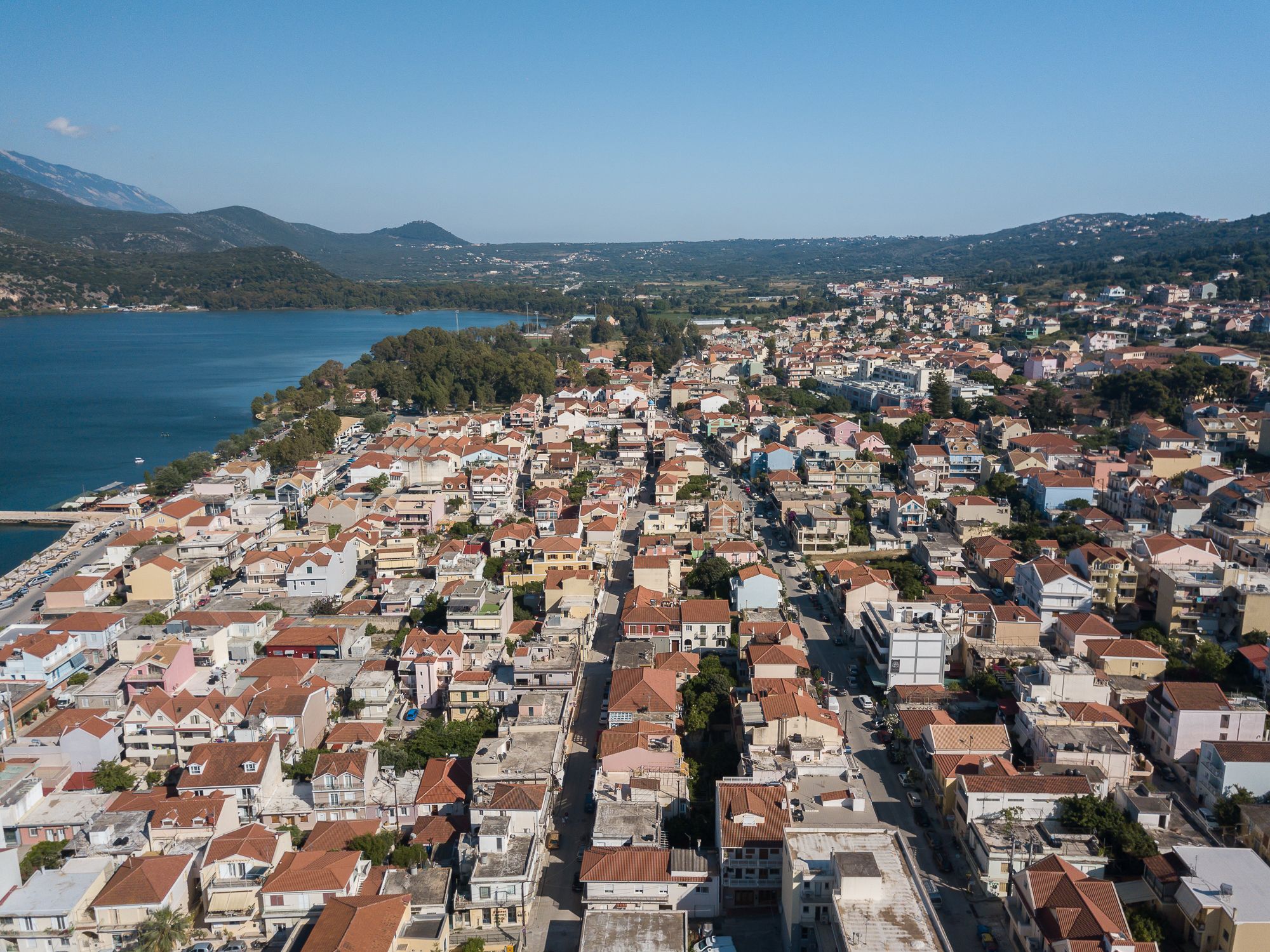 A coastal town with a dense cluster of buildings, a clear view of the sea, and a hilly backdrop.