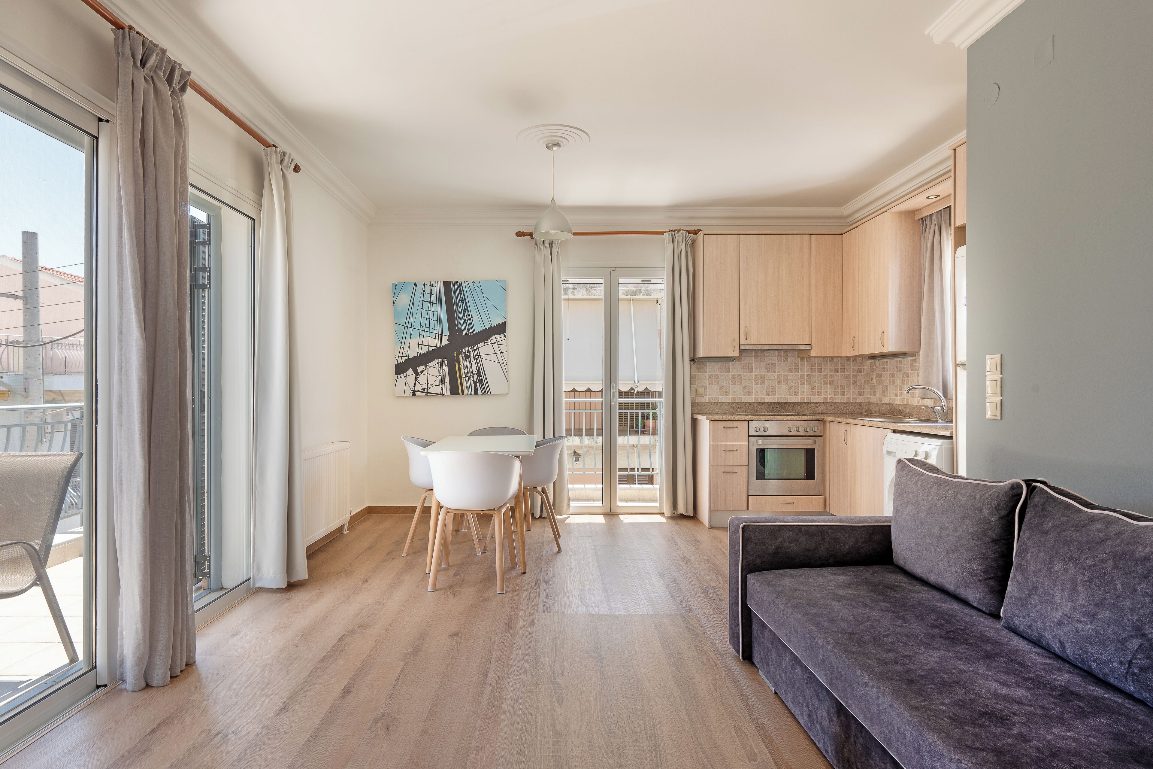 Un appartement moderne comprenant un coin repas, une cuisine et un canapé gris.