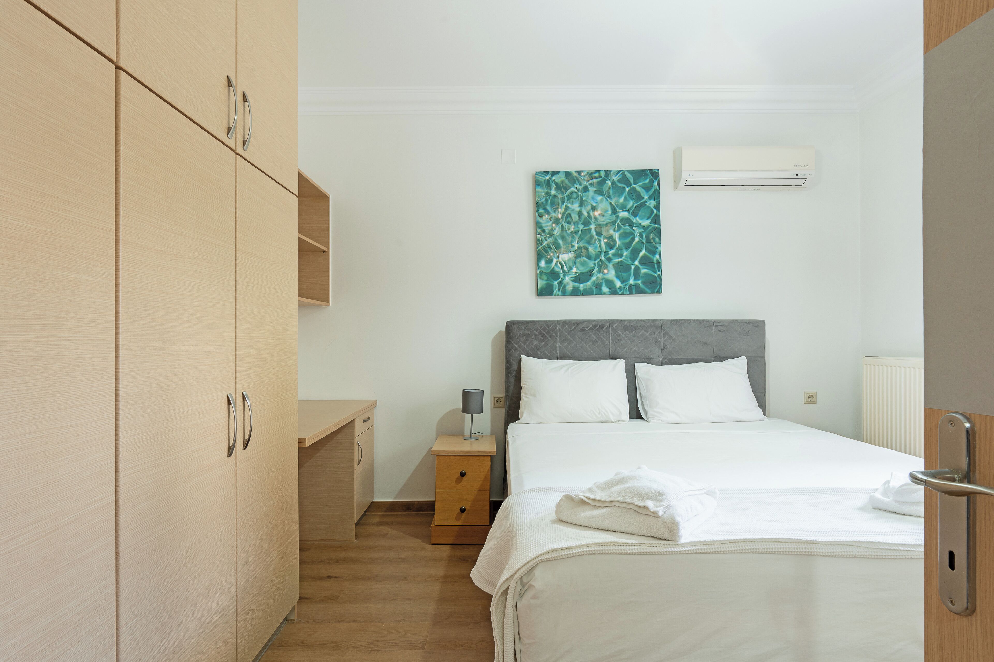 A hotel room with a bed, a nightstand, a desk, and a wardrobe.