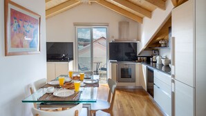 A modern kitchen with wooden beams, a dining area with breakfast set, and a view of the outside.