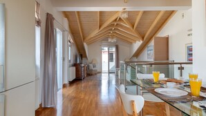 A spacious kitchen with wooden beams, a glass dining table, and a view to the outside.