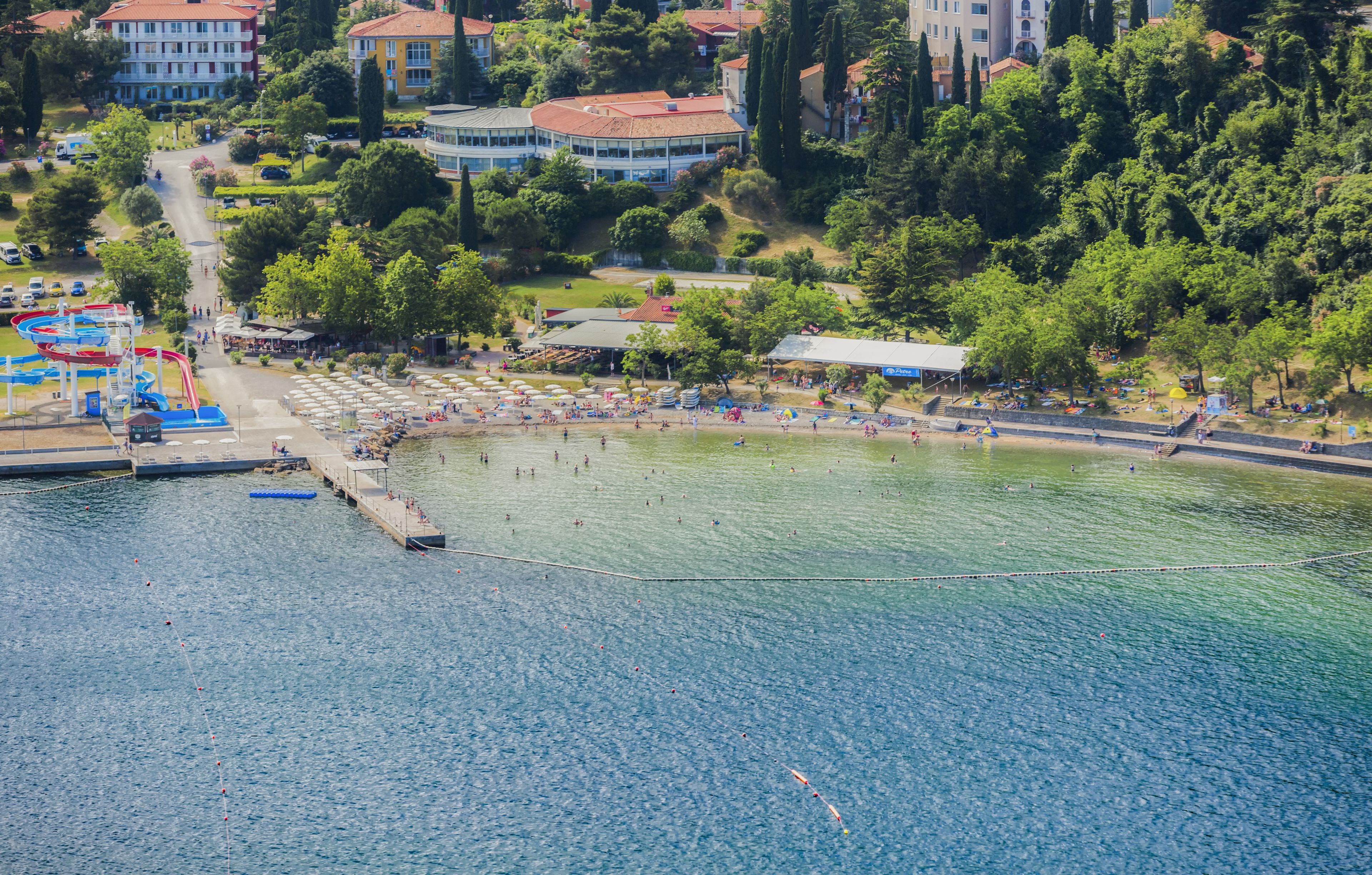 A waterfront area with a swimming pool, beach, and adjacent buildings.