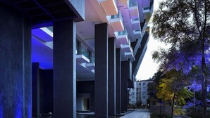 Un bâtiment moderne doté d’une cour intérieure, de grandes colonnes et d’un chemin bordé de plantes.