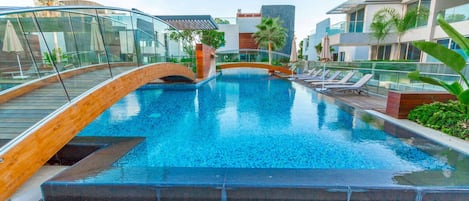 Una piscina al aire libre, sombrillas, sillones reclinables de piscina