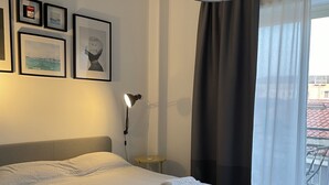 A neatly made bed with a grey headboard, a bedside lamp, and a small round table with a phone. - La Dimora delle Muse (Catania)