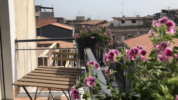 A balcony with a wooden table and a flower planter. - La Dimora delle Muse (Catania)