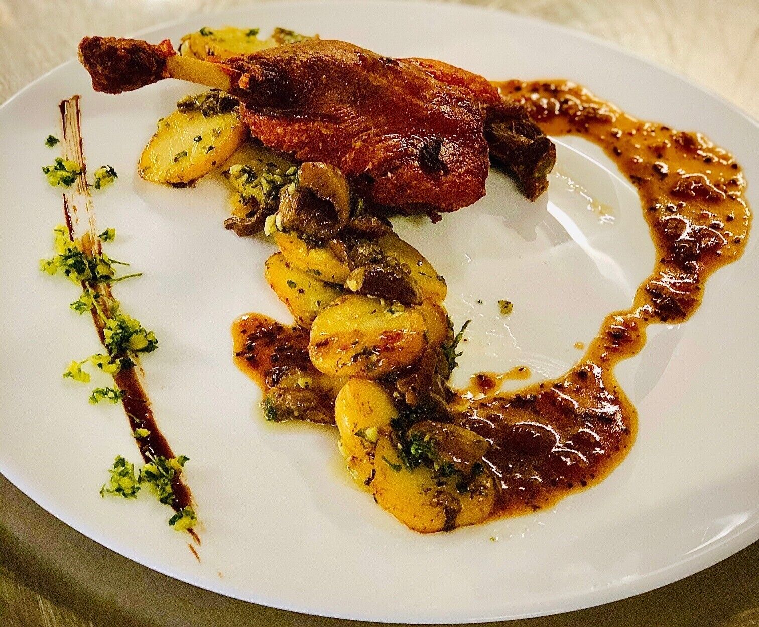 A plate of food with roasted meat and potatoes, garnished with herbs.