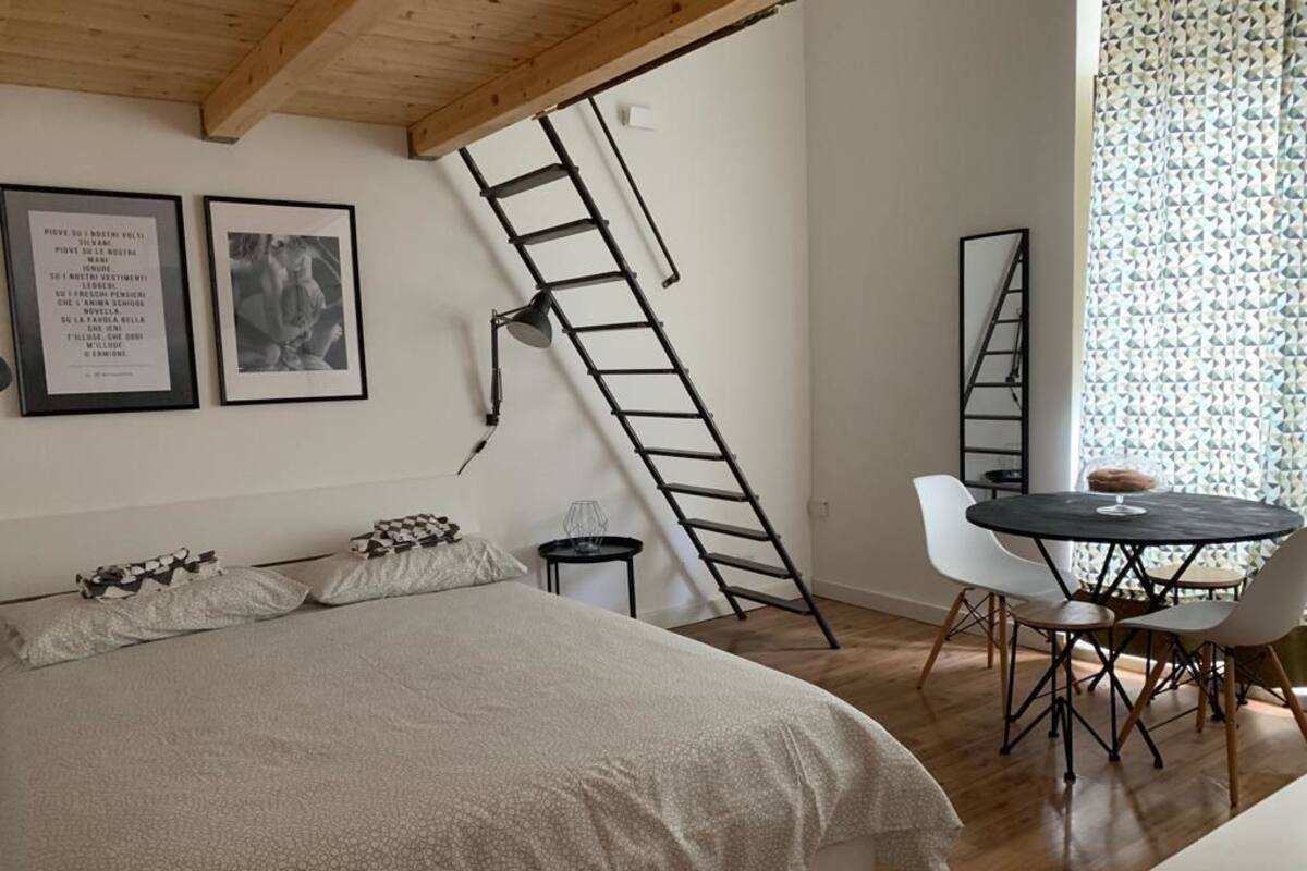 A bedroom with a bed, a desk, and a ladder.