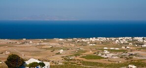 Un village côtier aux bâtiments blancs, offrant une vue dégagée sur la mer et un paysage vallonné.