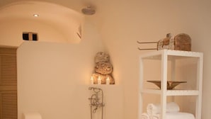 Une salle de bain moderne avec une baignoire aux lignes courbes, une étagère intégrée pour les serviettes et une douche murale.