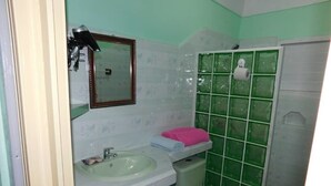 Une salle de bain comprenant un lavabo, des toilettes et une cabine de douche carrelée de carreaux verts.