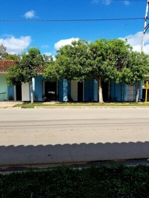 A row of blue buildings with trees in front. - Casa Colonial 1850 Tito y Yiya (Viñales)