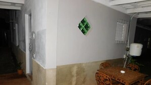 Un espace patio aménagé avec une table et des chaises, une plante en pot et un luminaire fixé au mur.