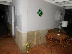 A patio area with a table and chairs, a potted plant, and a wall-mounted light fixture. - Casa Colonial 1850 Tito y Yiya (Viñales)