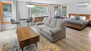 Un dormitorio moderno con sofá, mesa de madera, cama y vistas al exterior.