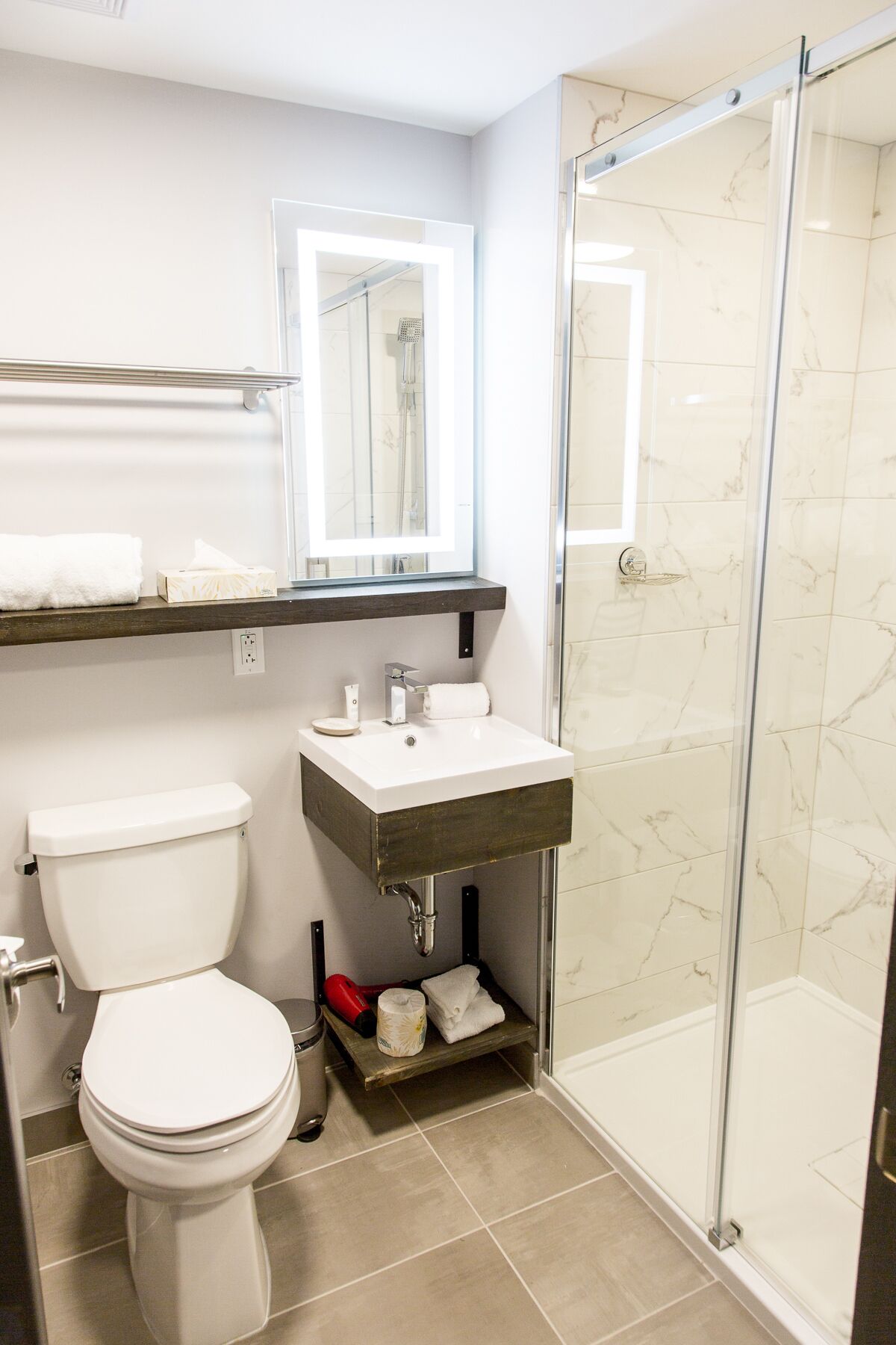Un baño con inodoro, lavamanos, espejo y zona de ducha.