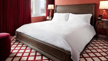 Una cama grande con sábanas blancas en una habitación con piso a cuadros rojo y blanco.