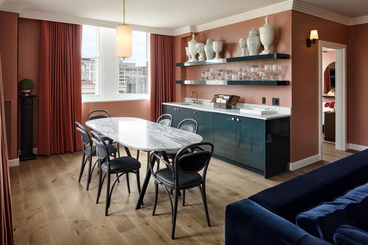 Un comedor moderno con una mesa de mármol, sillas oscuras y un sofá azul.