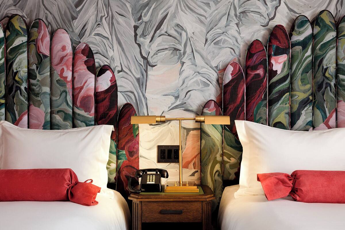 Una habitación de hotel con una cama, una mesita de noche, un teléfono y un espejo.