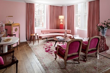 A dimly lit room with a red-tinted glass display case filled with trophies, a red carpet, and grey upholstered chairs. at Riggs Washington DC