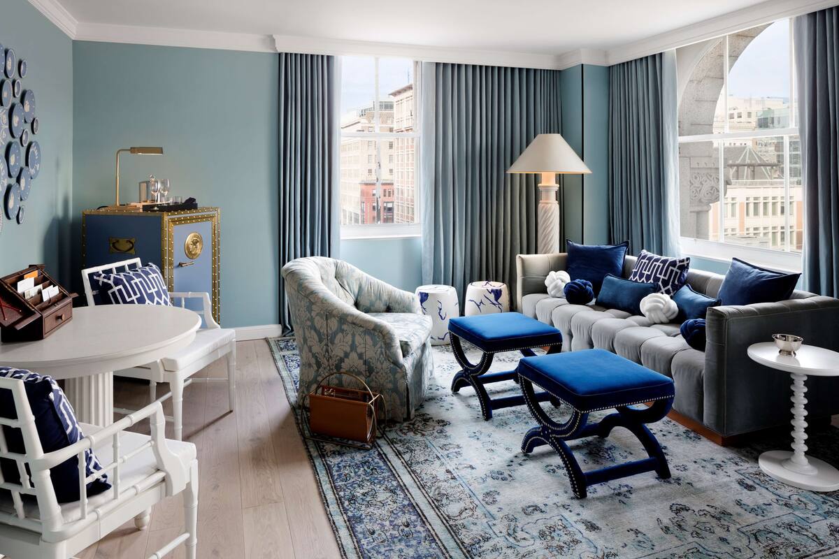 Una sala de estar moderna con un conjunto de sofás, un sillón estampado, una mesita y un aparador decorativo.