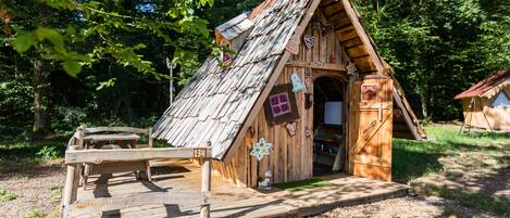 A rustic wooden cabin with a sloped roof, a wooden deck, and a small porch.